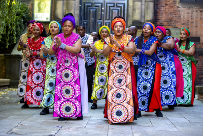 Photo of the Soweto gospel choir wearing brightly colored dresses and shirts.