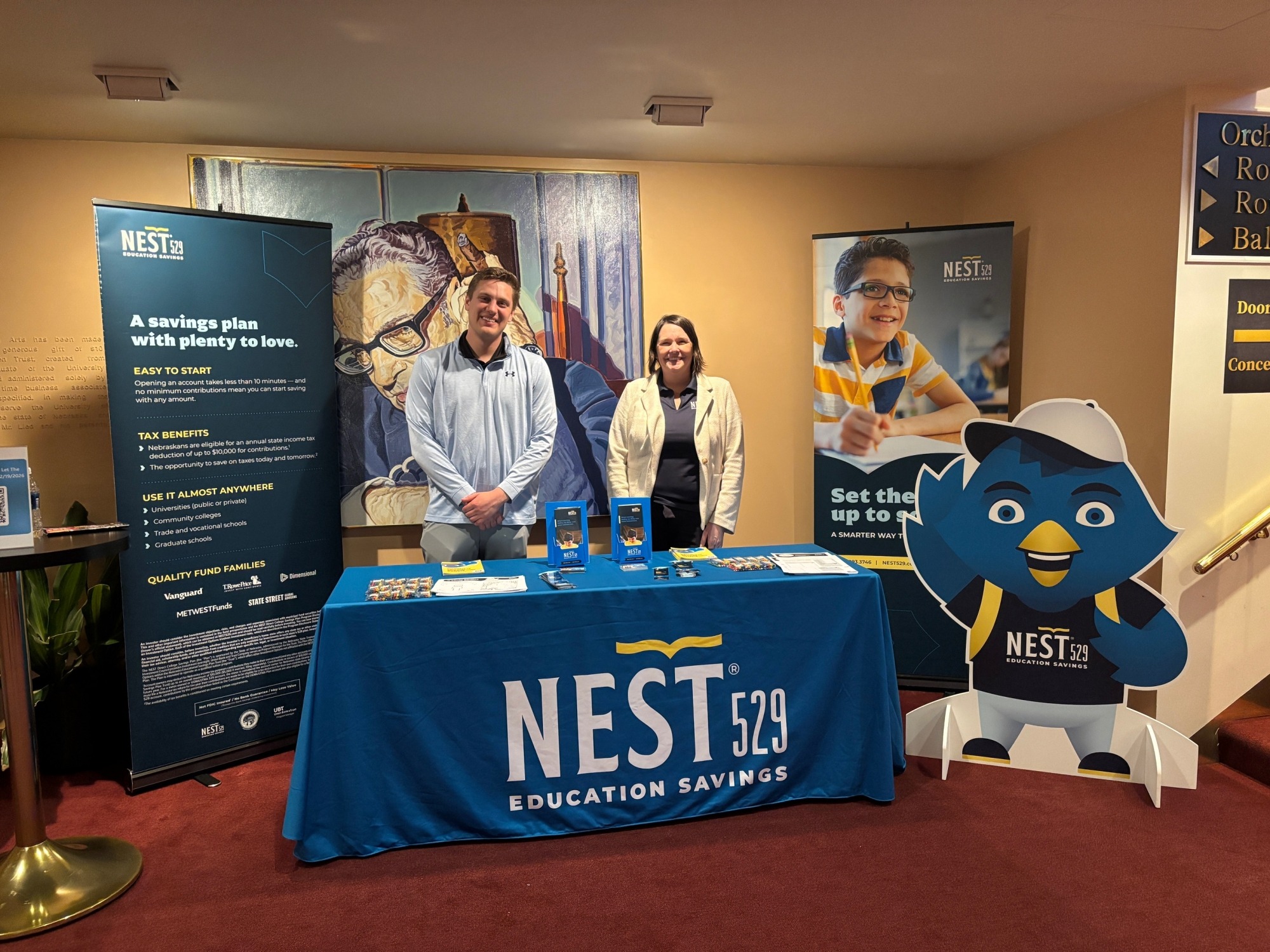 photo of the nest 529 table in the Lied Center lobby with two team members standing behind the table. 